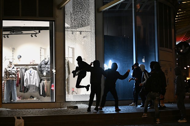 Youths break a store window during clashes between protesters and police in Paris.