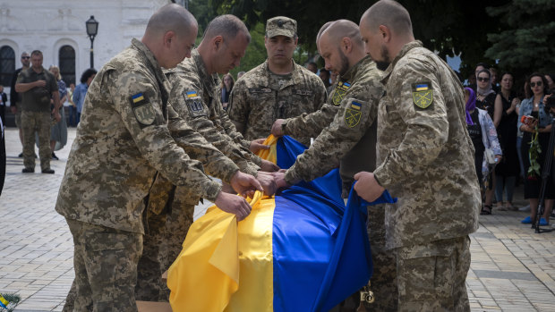Soldiers in Kyiv fold a Ukrainian flag on the coffin of a soldier killed Russian troops in a battle.