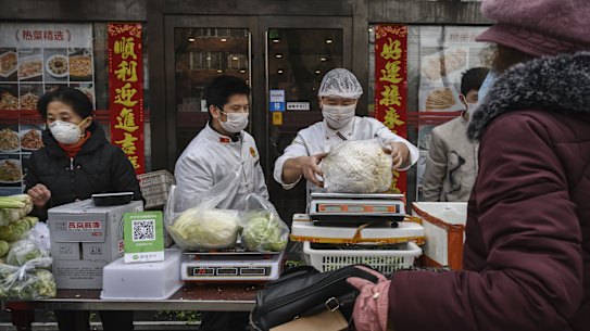 Chinese vendors wear protective masks as they sell vegetables in the street during the Chinese New Year holiday on Sunday in Beijing.