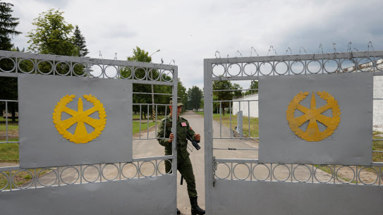 A Belarusian service member closes the gates of a disused base housing a tent camp set up for Wagner but unoccupied.