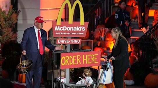 US President Donald Trump greets a family dressed as employees of a McDonald’s drive-through during a Halloween event on the South Lawn of the White House.
