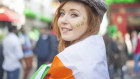 Smiling pretty red haired Irish girl with tweed hat, wrapped in the Irish flag and shamrocks painted on her face, Temple Bar, Dublin, Ireland.  iStock image for Traveller. Re-use permitted.
