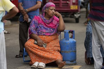 A Sri Lankan woman sits outside a police station in protest, demanding cooking gas.