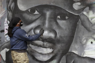 Artist Theo Ponchaveli paints a mural of the likeness of Ahmaud Arbery in Dallas.