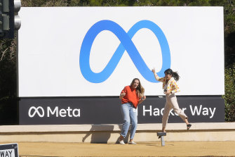Employees take a picture with the company's new name and Meta logo outside its headquarters in Menlo Park, California.