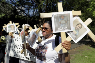 Nancy Pablo, with the Alianza Latina International, holds crosses with photos of victims of the Robb Elementary School shooting as she protests the National Rifle Association Annual Meeting.
