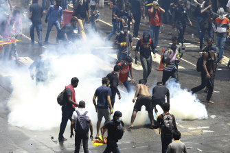 Protesters try to remove a tear gas shell after it was fired by police to disperse them in Colombo, Sri Lanka.