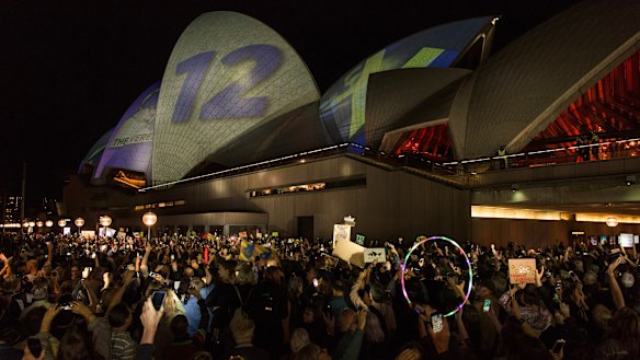 Protesters on the harbour foreshore opposing the projection of material, promoting the 2018 Everest Horse Race onto the sails of the Opera House.