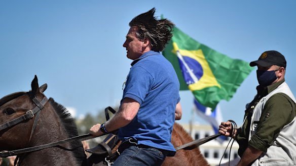 Brazilian President Jair Bolsonaro rides a horse greeting supporters outside the presidential palace in Brasilia on Sunday.