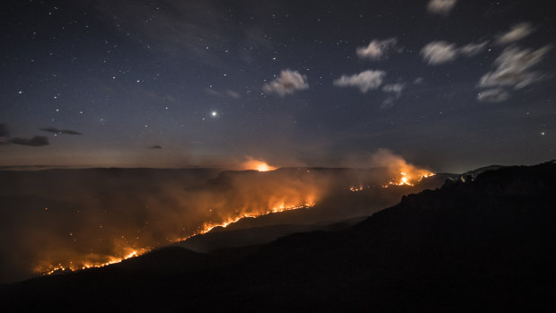 The Ruined Castle Fire burns under strong westerly winds in front of Mount Solitary at Echo Point in Katoomba.