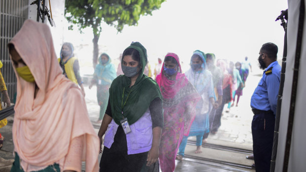 Masked garment workers walk through a disinfection at a factory in Savar, Bangladesh.