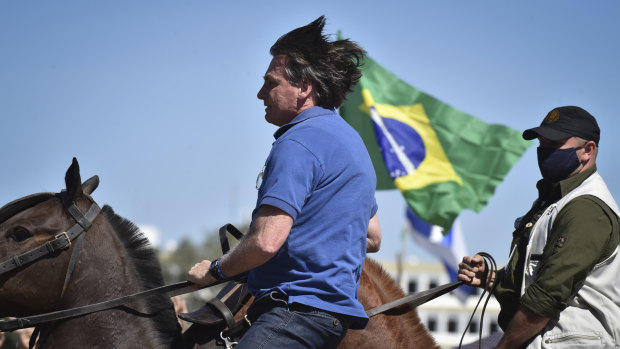 Brazilian President Jair Bolsonaro rides a horse greeting supporters outside the presidential palace in Brasilia on Sunday.