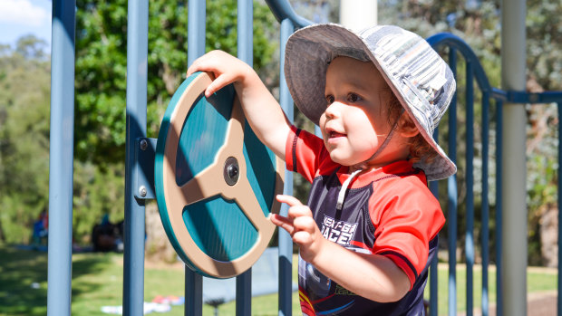 Lachlan Bush gets to grips with a steering wheel at the Cotter Avenue Playground.