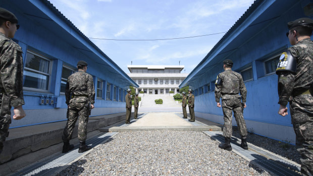Four North Korean soldiers and four South Korean soldiers stand at the border village of Panmunjom in the Demilitarized Zone.