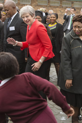 British Prime Minister Theresa dances with children during a visit to the ID Mkhize High School in Gugulethu, Cape Town, South Africa.