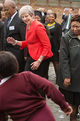 British Prime Minister Theresa dances with children during a visit to the ID Mkhize High School in Gugulethu, Cape Town, South Africa.