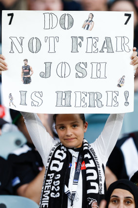 A young Magpies fan holds a banner in support of Josh Daicos of the Magpies.