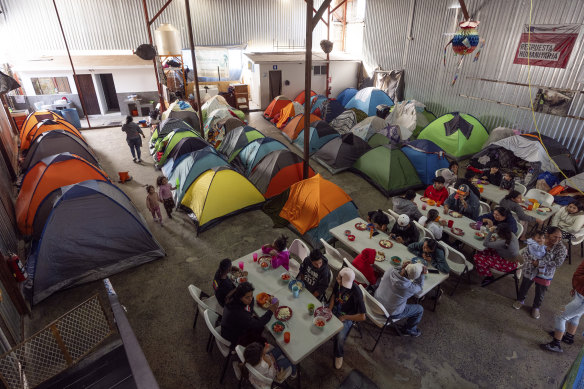 Migrants eat at a shelter set up in Mexico near the US border.