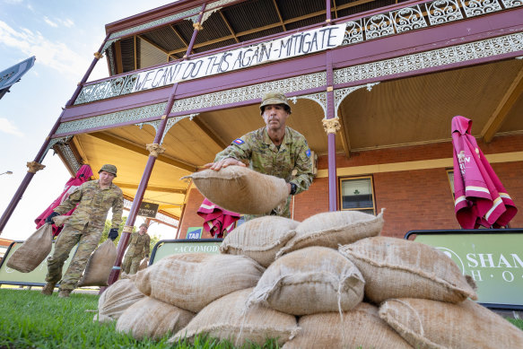 Members of the armed forces remove sand bags from businesses in the main street of Rochester.