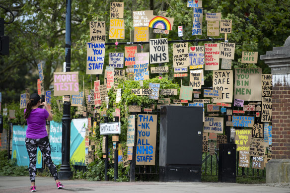 A woman takes a photo in-front of signs in support of the NHS and key workers in East London on Saturday in London, England.