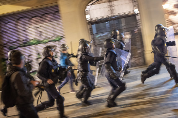 National police officers run behind demonstrators during a protest in Barcelona ahead of Sunday's general election.