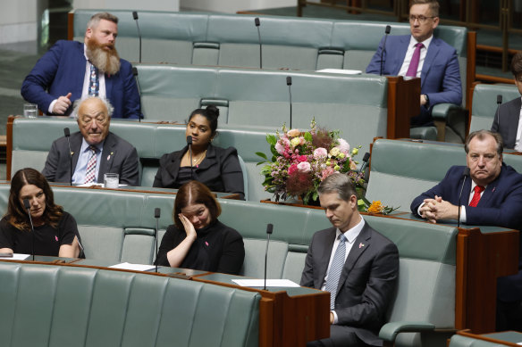 A bouquet of flowers is placed on the desk of Peta Murphy, as Labor MP Lisa Chesters wipes her eyes during the condolence motion.