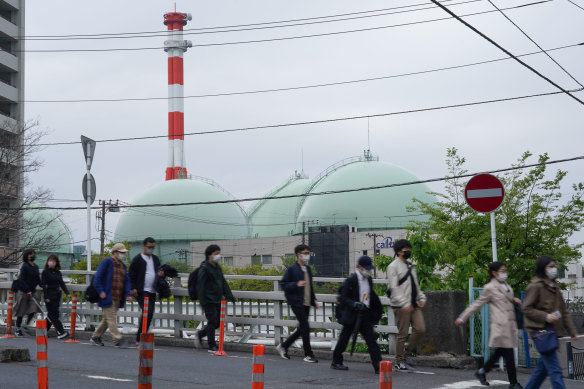 Pedestrians walk by Tokyo Gas Co. storage tanks in Yokohama. Japan has become more reliant on fossil fuels following the Fukushima disaster.