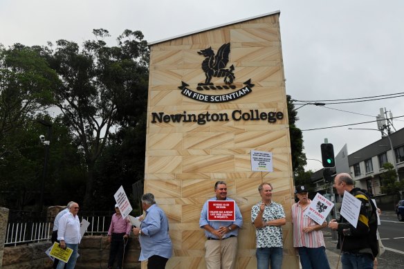 Former students and parents of students at Newington College holding protest signs at the entrance of the private boys college. 