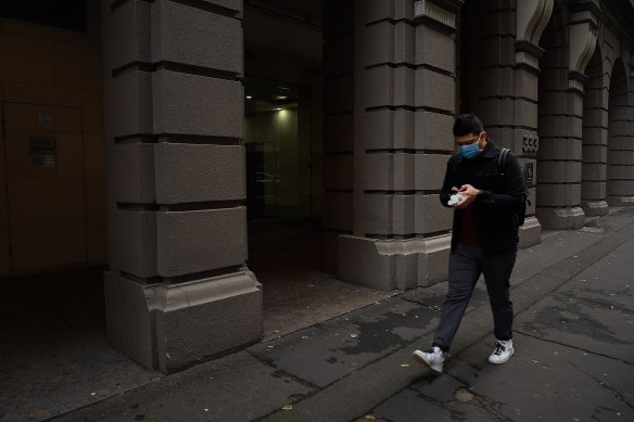 A man wearing a face mask walks along Kent street in the Sydney CBD.