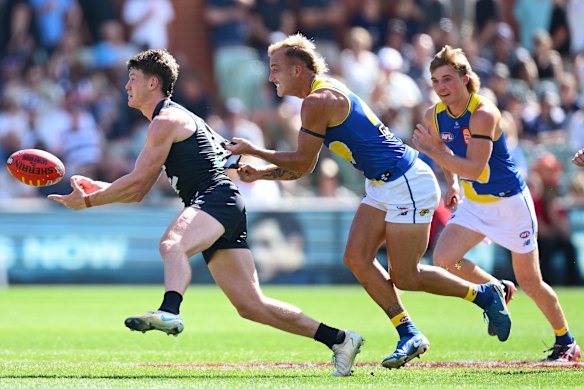 Carlton’s Sam Walsh handballs while being tackled.
