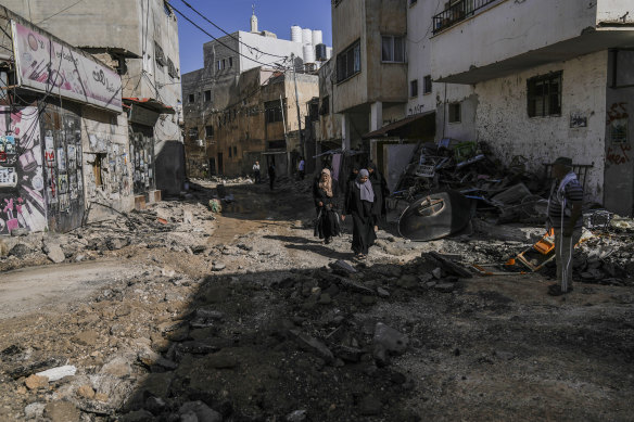 Palestinians walk past an area damaged after an Israeli military raid in Jenin refugee camp in the West Bank.