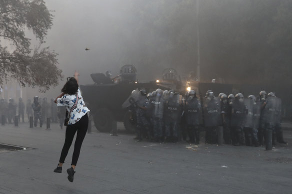 An anti-government protester throws a stone towards riot police during a protest near Parliament Square, Beirut, Lebanon, on Tuesday.
