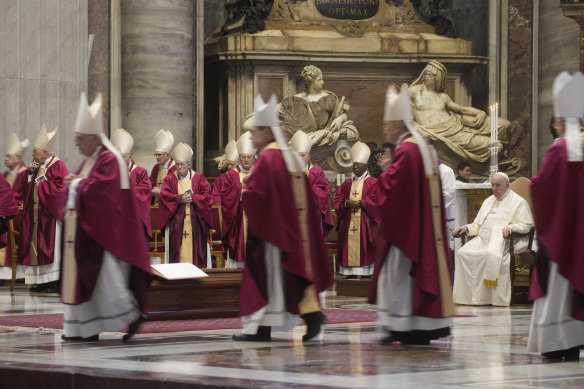 Pope Francis sits as cardinals and bishops leave after the mass.