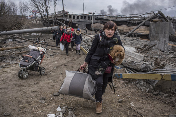 People cross an improvised path under a destroyed bridge while fleeing the town of Irpin, Ukraine, on Sunday.