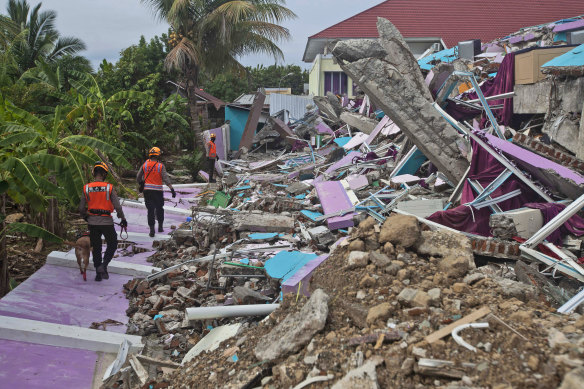 Members of police K-9 squad lead a sniffer dog during a search for victims at a hospital building collapsed in Friday's earthquake in Mamuju, West Sulawesi.