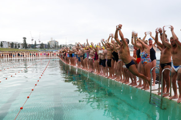 Swimmers jump in the pool with a block of ice to open the season at the Bondi Icebergs.