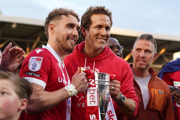 Ryan Reynolds, co-owner of Wrexham AFC, poses for a photo with the trophy alongside Sam Smith following the club’s promotion.