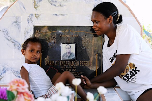 Filomena Zennefer Pereira Ekuttan, 24, and her daughter Grace, 4, at her mother’s grave near Batugade village. Maria de Encarnacao Pereira died of cervical cancer.