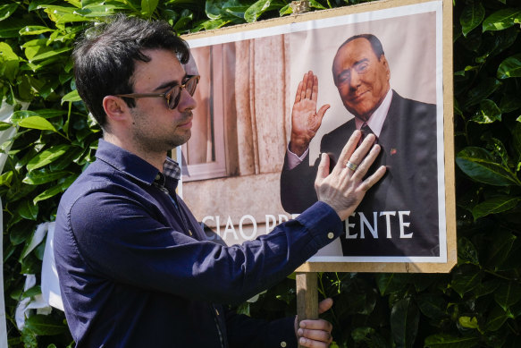 A man poses next to a poster of Silvio Berlusconi outside the former prime minister’s residence in Arcore, near Milan.