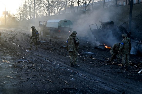 Ukrainian service members collect unexploded shells after fighting with Russia.