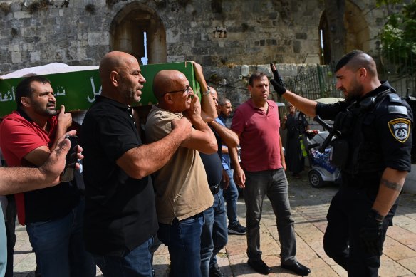 Muslim worshippers carrying a coffin are stopped momentarily by an Israeli police officer before entering the Al Aqsa Mosque in Jerusalem.