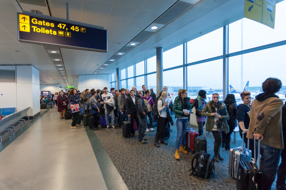 Air passengers queued up waiting in a London airport.