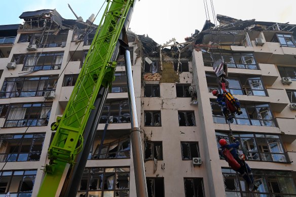 During a recovery operation, emergency search and rescue personnel are lifted by a crane to the top of apartment building that was hit by a missile attack on June 26 in the Shevchenkivs’kyi district central Kyiv.