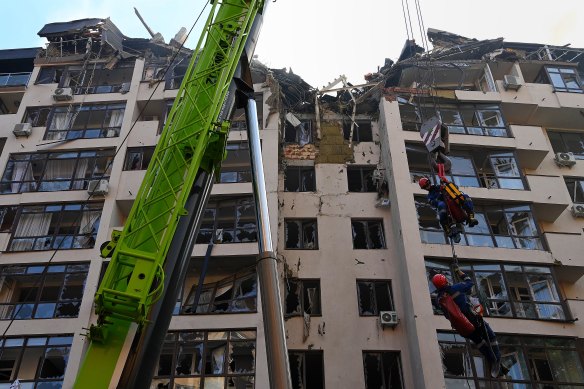 During a recovery operation, emergency search and rescue personnel are lifted by a crane to the top of apartment building that was hit by a missile attack on June 26 in the Shevchenkivs’kyi district central Kyiv. 