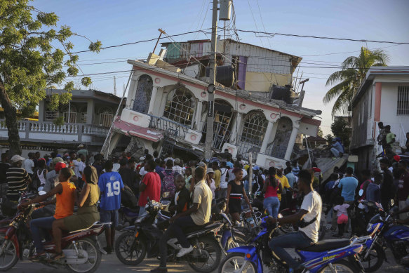 People gather outside the Petit Pas Hotel, destroyed by the earthquake in Les Cayes, Haiti by a 7.2 magnitude earthquake.