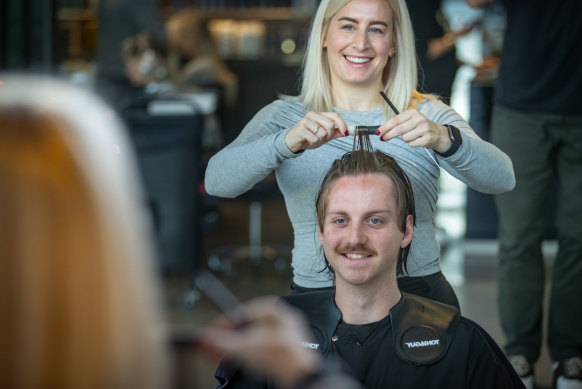 Perm specialist Laura Szakaly applying rollers in a customer’s hair.