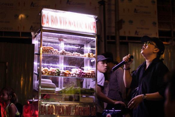 A street vendor passes a karaoke singer on Bui Vien Street, Ho Chi Minh, Vietnam. 