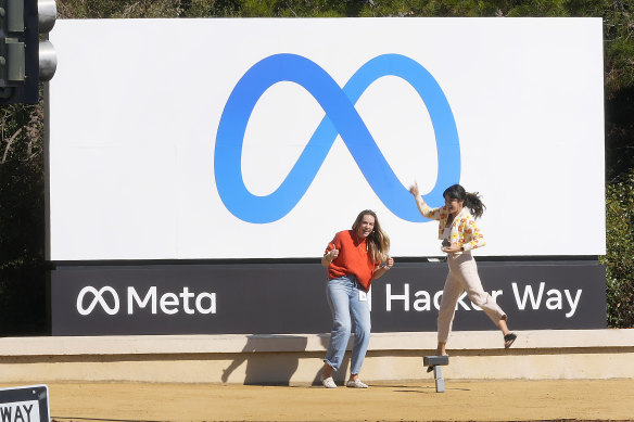 Employees take a photo with the company’s new name and logo Meta outside its headquarters in Menlo Park, California.