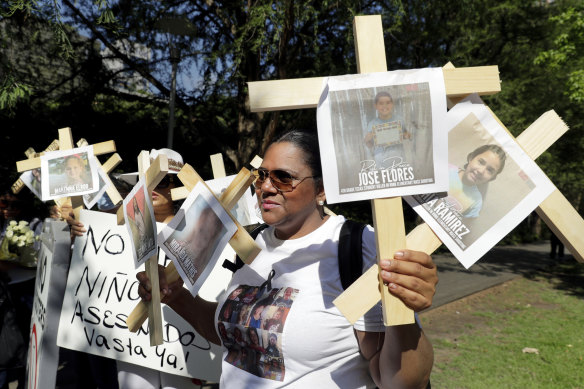 Nancy Pablo, with the Alianza Latina International, holds crosses with photos of victims of the Robb Elementary School shooting as she protests the National Rifle Association Annual Meeting.
