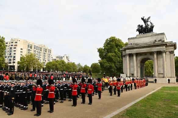 The coffin of Queen Elizabeth II with the Imperial State Crown resting on top, borne on the state gun carriage of the Royal Navy, followed by members of the royal family, proceeds past the Wellington Arch.